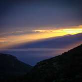 Golden glühende BerGolden glühende Bergkette mit flach einfallenden Lichtstrahlen und Regenwolken über Thassos. gkette mit flach einfallendenLichtstahlen