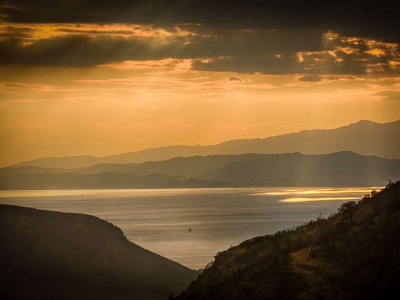 Goldene Lichtstimmung bei einem Sonnenuntergang mit Lichtflecken auf dem Meer im Frühling.